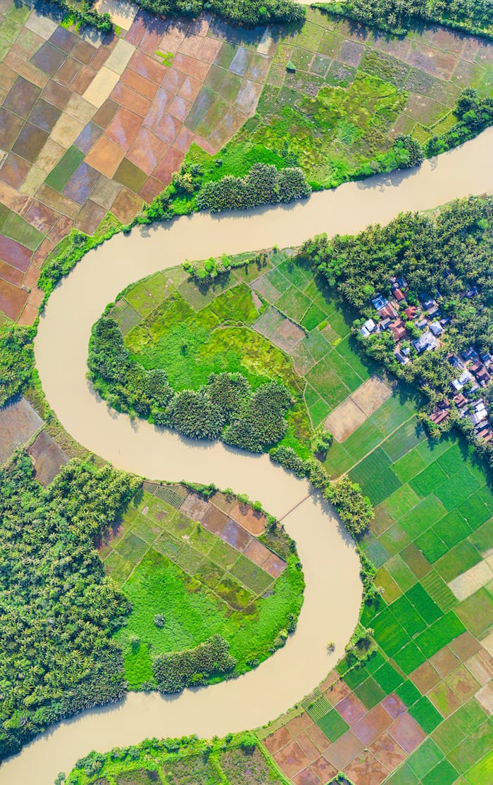 Explore the vibrant aerial landscape of Banten, Indonesia, showcasing lush farmland and winding river.