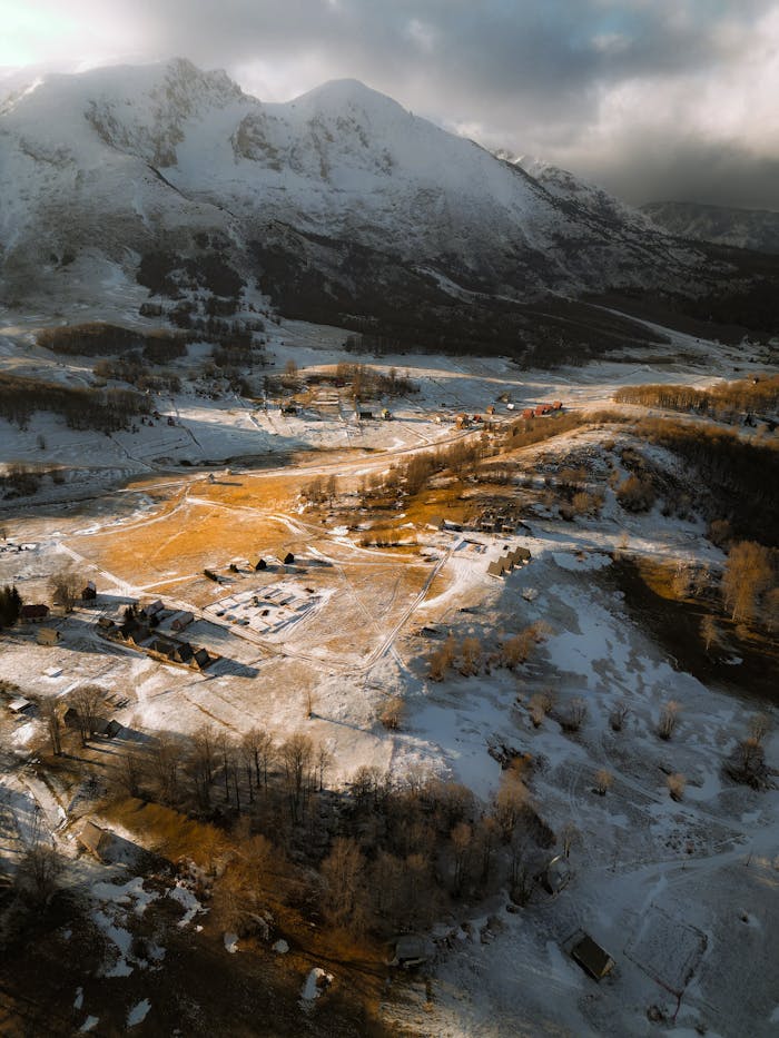 Aerial view of a snowy mountain village surrounded by majestic peaks.